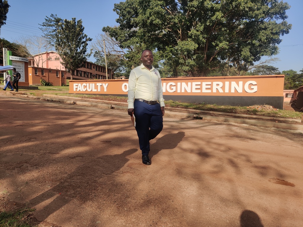 Tumwesigye patrick stading on the display wall of the engineering faculty